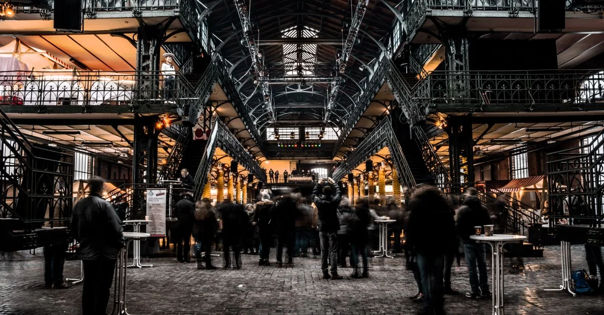 Marché intérieur animé avec une architecture en fer vintage et une foule agitée, capturant le commerce urbain.