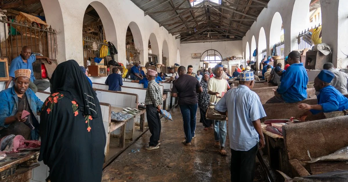 Des personnes engagées dans un commerce animé à l'intérieur d'un hall de marché aux poissons spacieux, mettant en valeur la culture locale.
